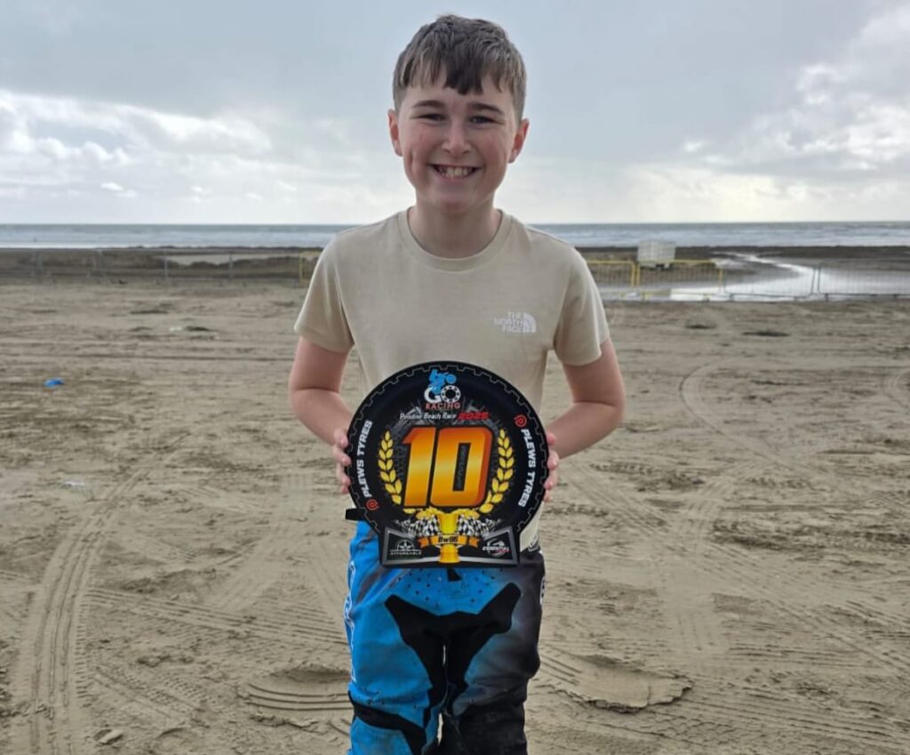 Child on a beach holding a trophy